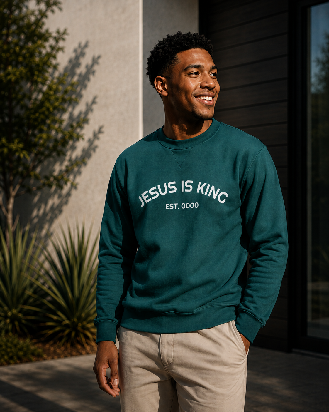 Male model wearing green Jesus Is King Christian sweatshirt by Daniel Haus Goods, styled as modern faith-based apparel.