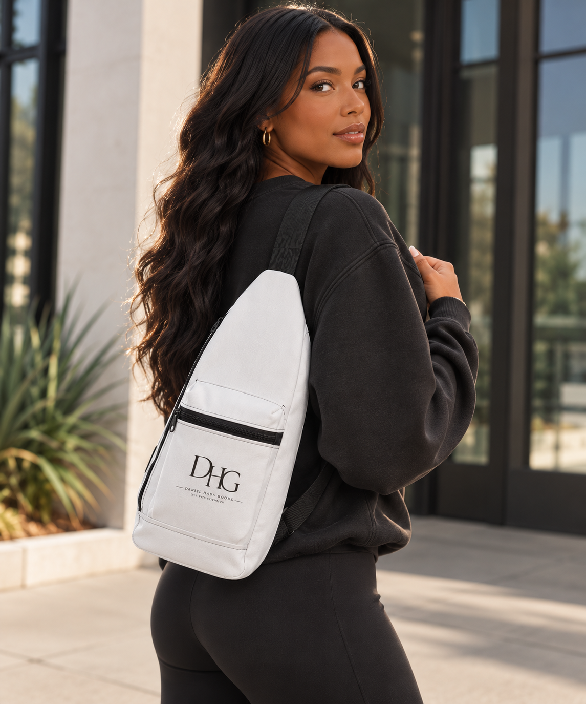Female model styling a Daniel Haus Goods crossbody sling bag with modern faith-inspired clothing.